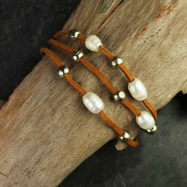 Wit zoetwater parel armband met bruin leer en magneetslot liggend op hout | Aafke