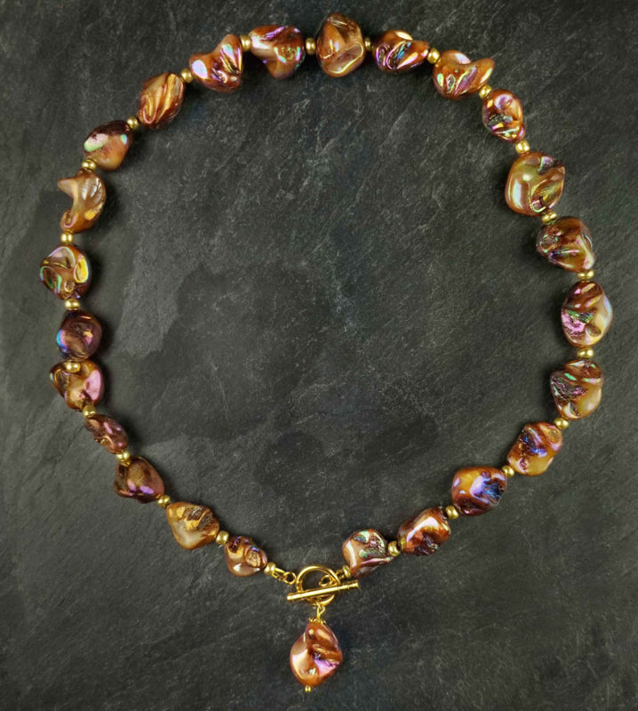Bruin parelmoeren schelpen ketting met goud edelstaal liggend op leisteen | set Shell AB Brown Gold