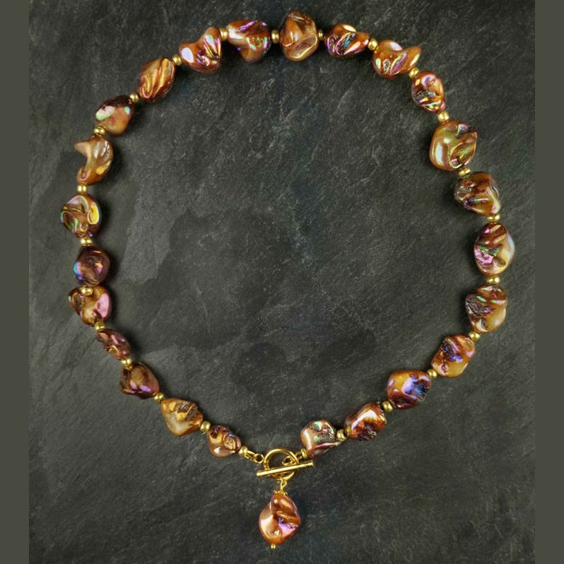 Bruin parelmoeren schelpen ketting met goud edelstaal liggend op leisteen | set Shell AB Brown Gold