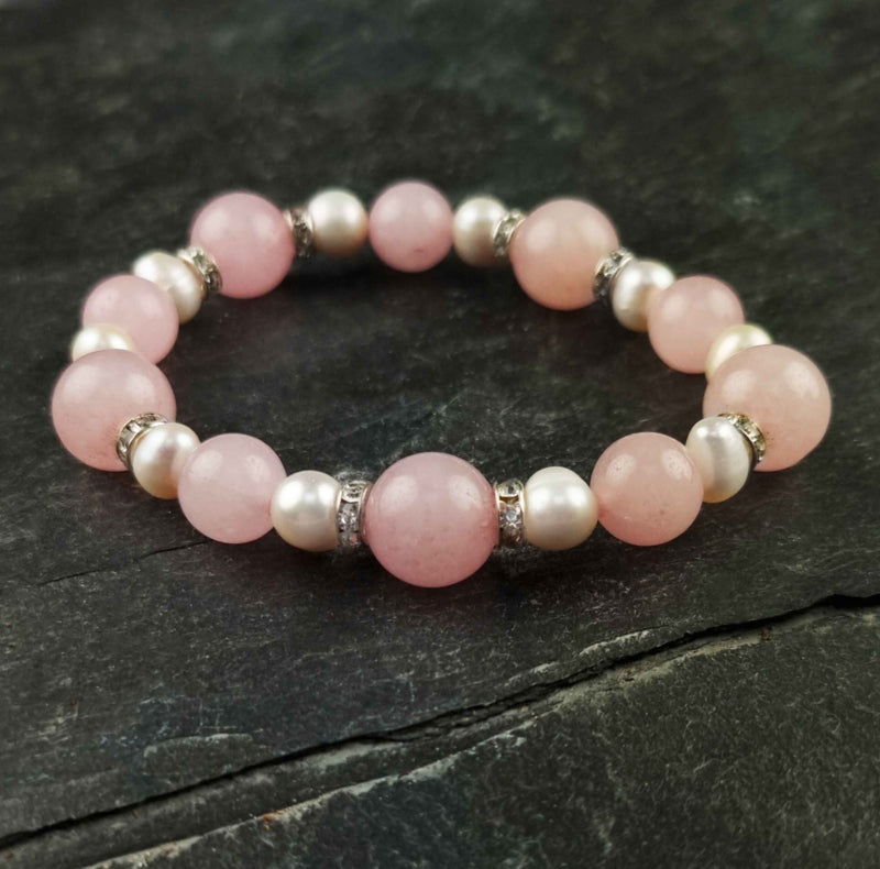 Wit zoetwater parel armband met roze edelstenen rozenkwart en stras steentjes , elastisch, liggend op leisteen | Bling Paerl W Rose Quartz
