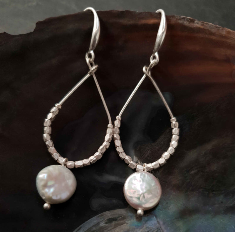 Lange witte zoetwater parel oorbellen met witte coin parel en mat zilver hangend in schelp | Milany Silver