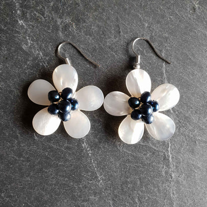 Zoetwater parel oorbellen met blauwe parels en wit parelmoer in bloem vorm met zilver edelstaal liggend op leisteen | White Shell Flower Blue Pearl