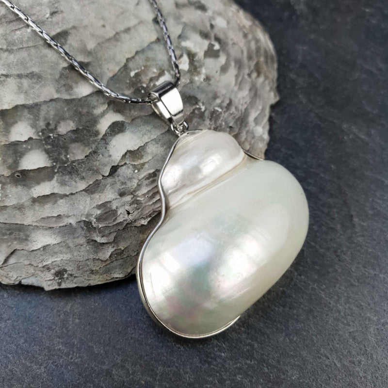 Witte parelmoeren schelpen ketting met zilver edelstaal liggend tegen schelp | Pearl White Turbo Shell