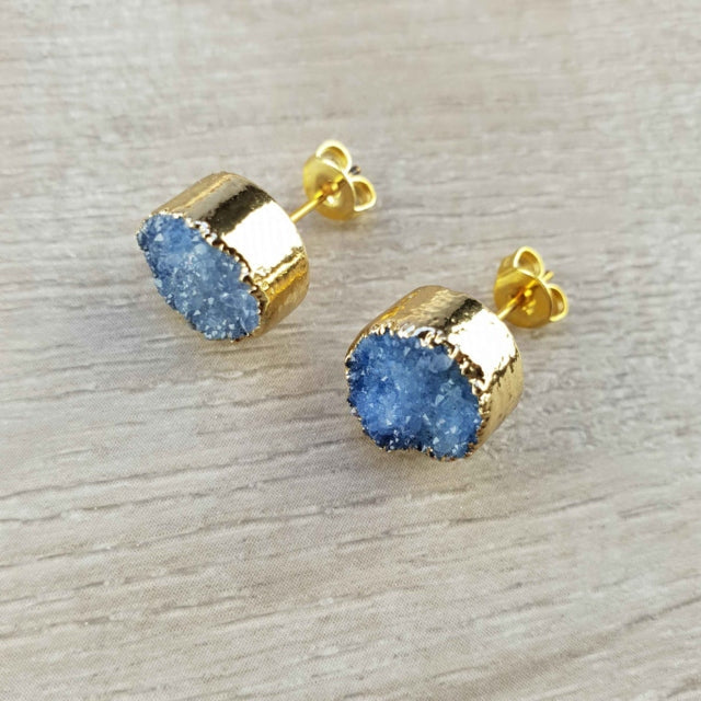 Blauwe edelstenen oorbellen met druzy agaat en goud liggend op hout, blauwe edelstenen oorknopjes | Druzy Gold Royal Blue