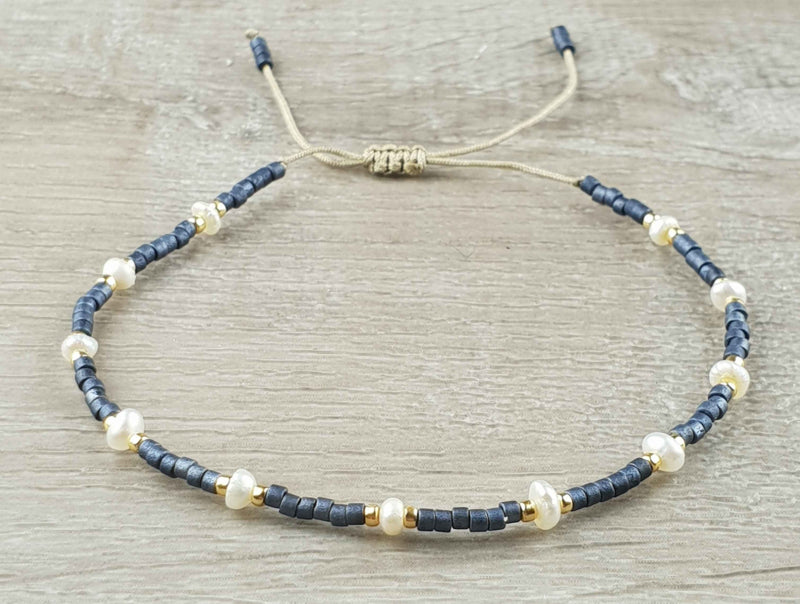 Wit zoetwater parel armband met blauwe en gouden kraaltjes en schuifsluiting liggend op hout | Mini Pearl Bead Pursian Blue