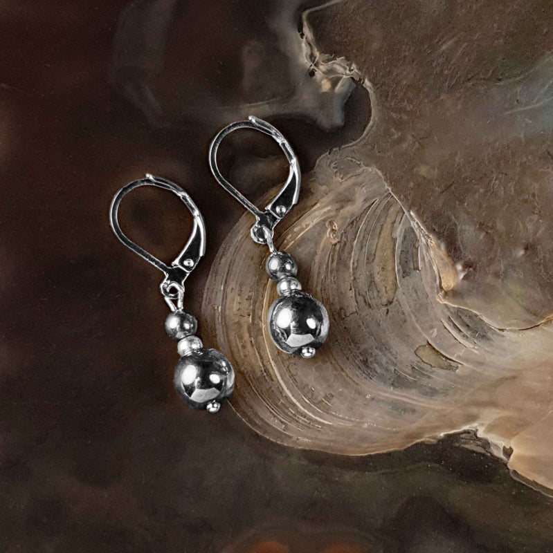 Edelstenen oorbellen met zilver hematiet en edelstaal liggend in schelp | Bold Silver Hematite