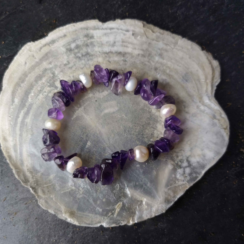 Wit zoetwater parel armband met paarse edelsteen amethist, elastisch parel armband, liggend op witte schelp | Pearl Amethyst Chip