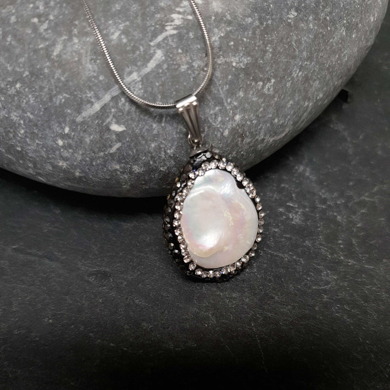Detail van zoetwater parelketting met witte parel hanger met stras steentjes en zilver edelstaal liggend op kei | Bright Minimal Silver Teardrop
