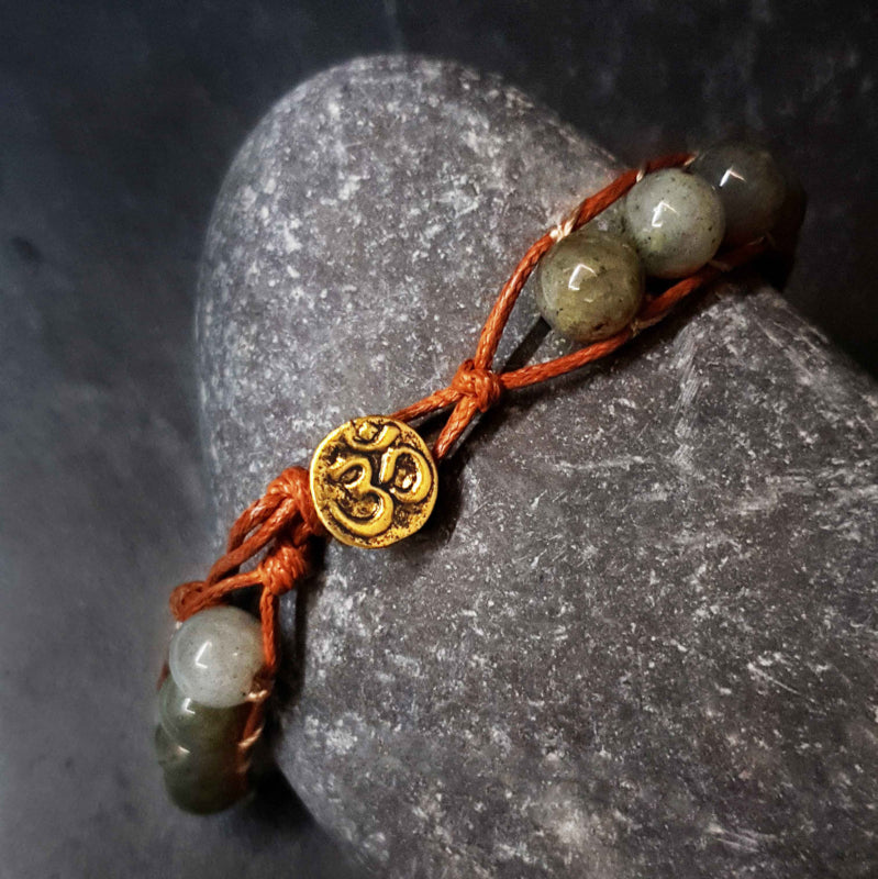 Edelstenen armband met labradoriet en gouden slotje met aum motief liggend op kei | Labradorite Antique Gold