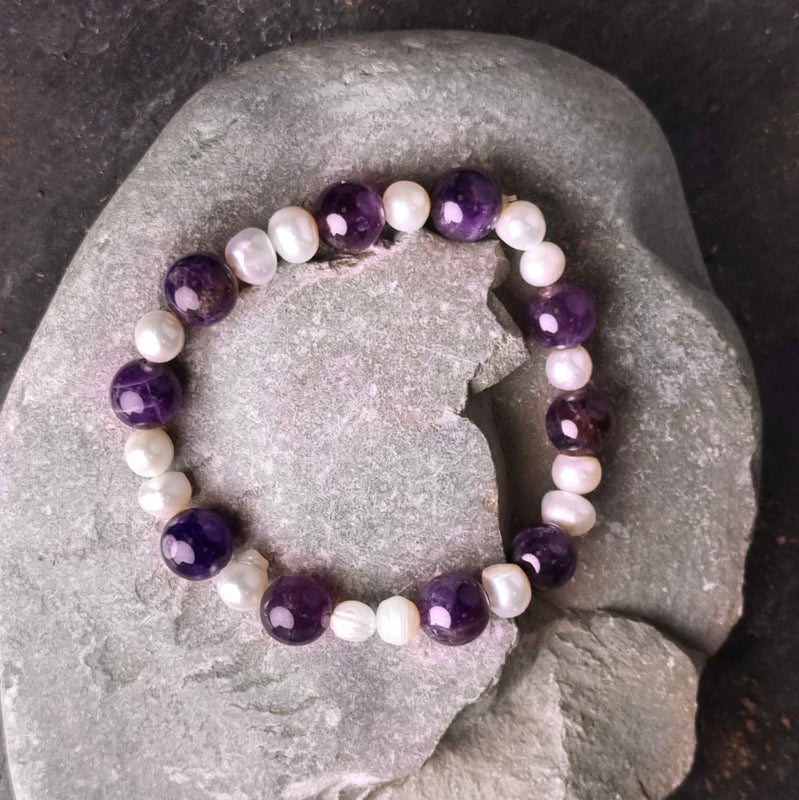 Zoetwater parel armband met witte parels en paarse edelsteen amethist liggend op kei | Pearl Amethyst