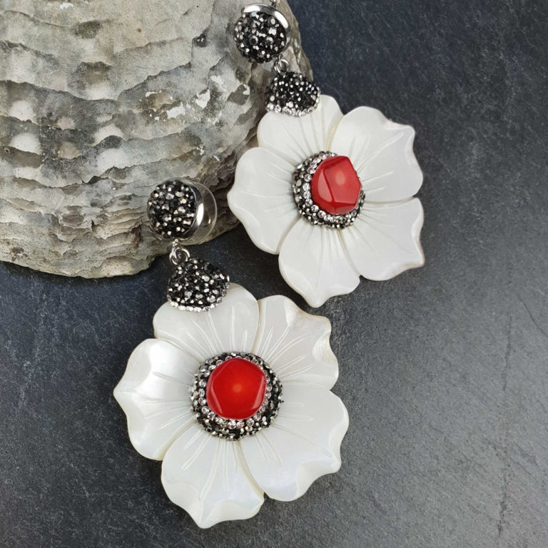 Koralen oorbellen met wit parelmoer bloem en stras steentjes liggend tegen schelp | Bright Coral Flower