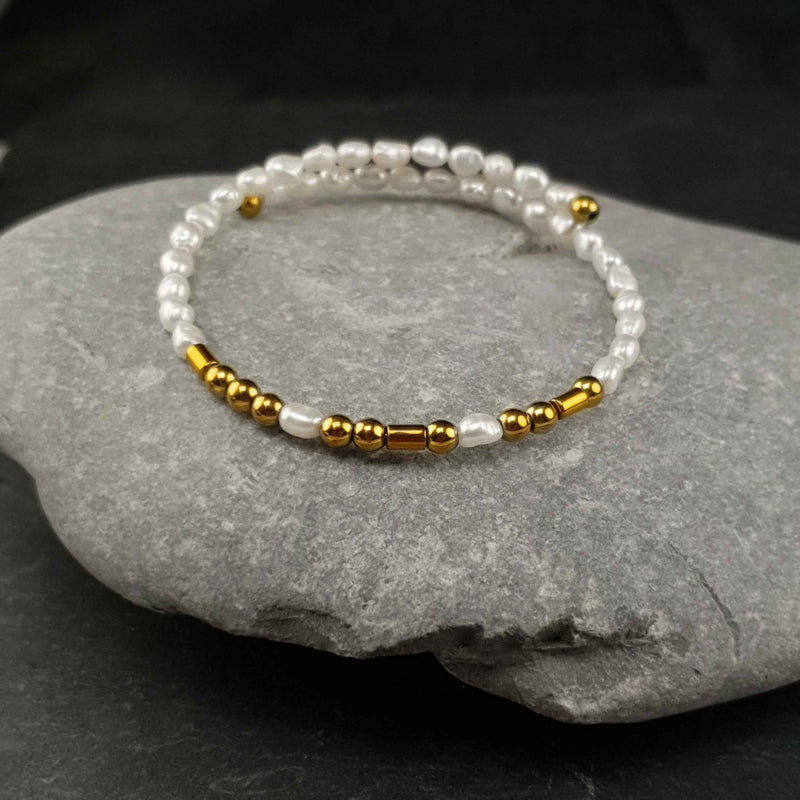 Wit zoetwater parel wikkelarmband met edelsteen goud hematiet liggend op kei | Cadeau set zoetwater parel armband Morse Code BFF Pearl Gold
