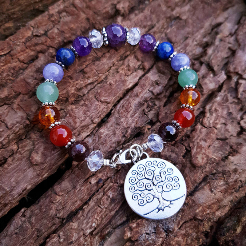Edelstenen armband met verschillende soorten en kleuren edelstenen en levensboom bedeltje liggend op schors | Gemstone Chakra