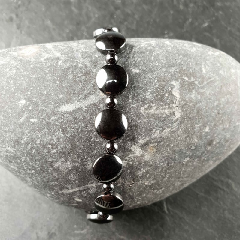 Zwarte edelstenen armband met hematiet liggend op kei | set Hematite Coin (AO)