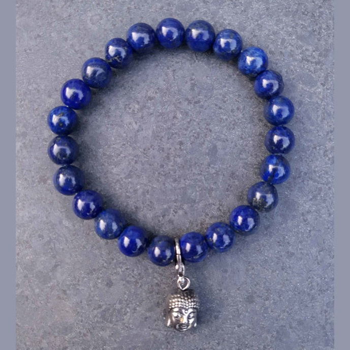 Blauw edelstenen armband met lapis lazuli en boeddha bedeltje liggend op leisteen | Lapis Lazuli Silver Dangling Buddha Head