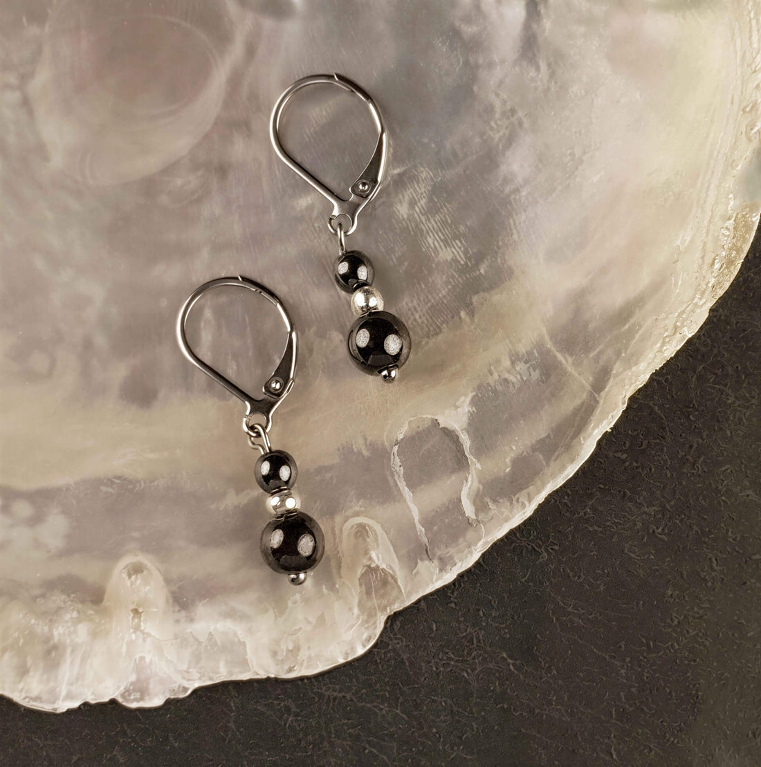 Zwarte edelstenen oorbellen met hematiet en zilver edelstaal liggend op witte schelp | Double Hematite Silver