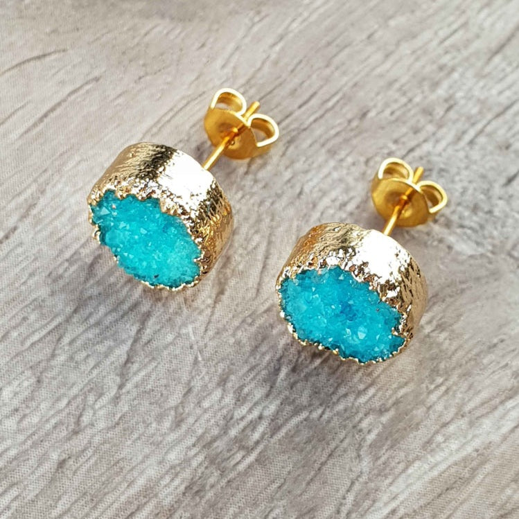 Edelstenen oorknoppen met aqua blauwe druzy agaat en goud liggend op hout bovenaanzicht| Druzy Gold Deep Sky Blue