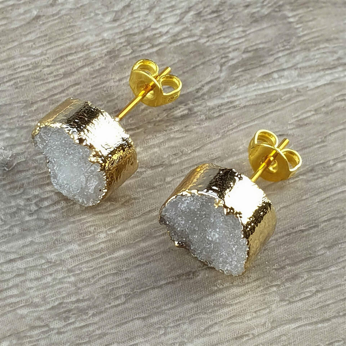 Edelstenen oorbellen met grijze druzy agaat en goud liggend op hout | Druzy Gold Grey