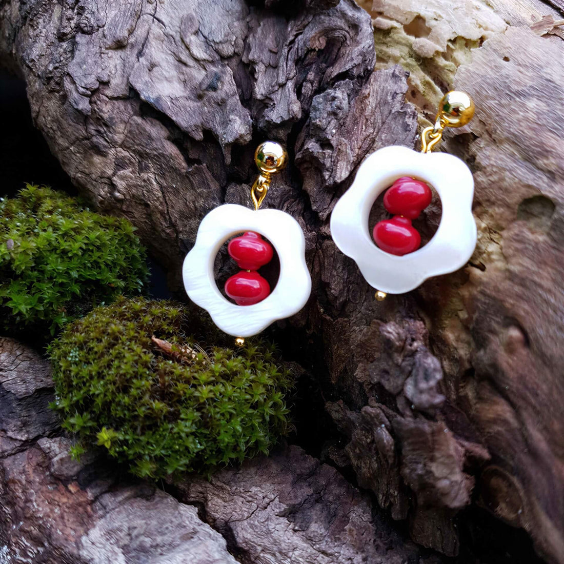 Rood koralen oorbellen met wit parelmoer in bloem vorm en goud edelstaal liggend op hout | Coral Flower