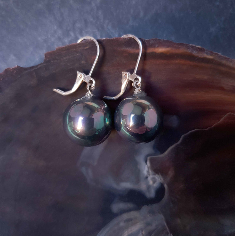 Petroleum kleurige ronde parel oorbellen met zilver edelstaal hangend aan schelprand | Verme Big Ball