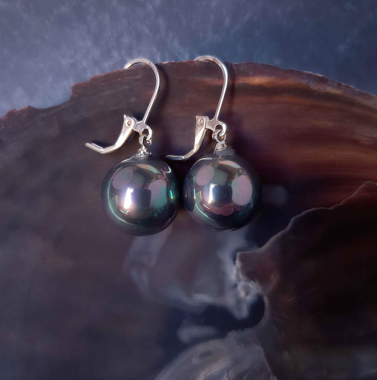 Petroleum kleurige ronde parel oorbellen met zilver edelstaal hangend aan schelprand | Verme Big Ball
