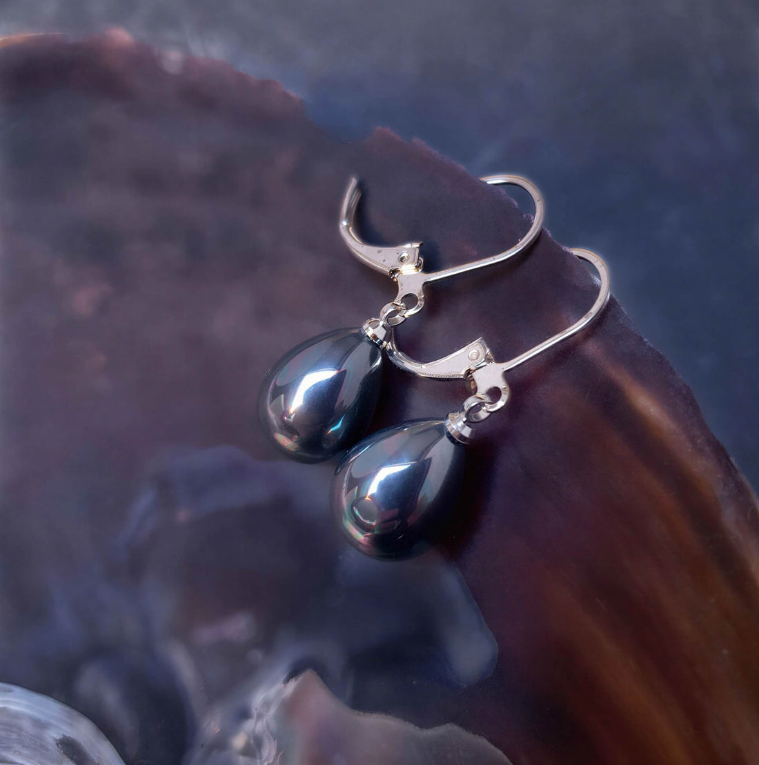Petroleum kleurige parel oorbellen in druppel vorm met zilver edelstaal liggend in schelp | Verme Teardrop Small