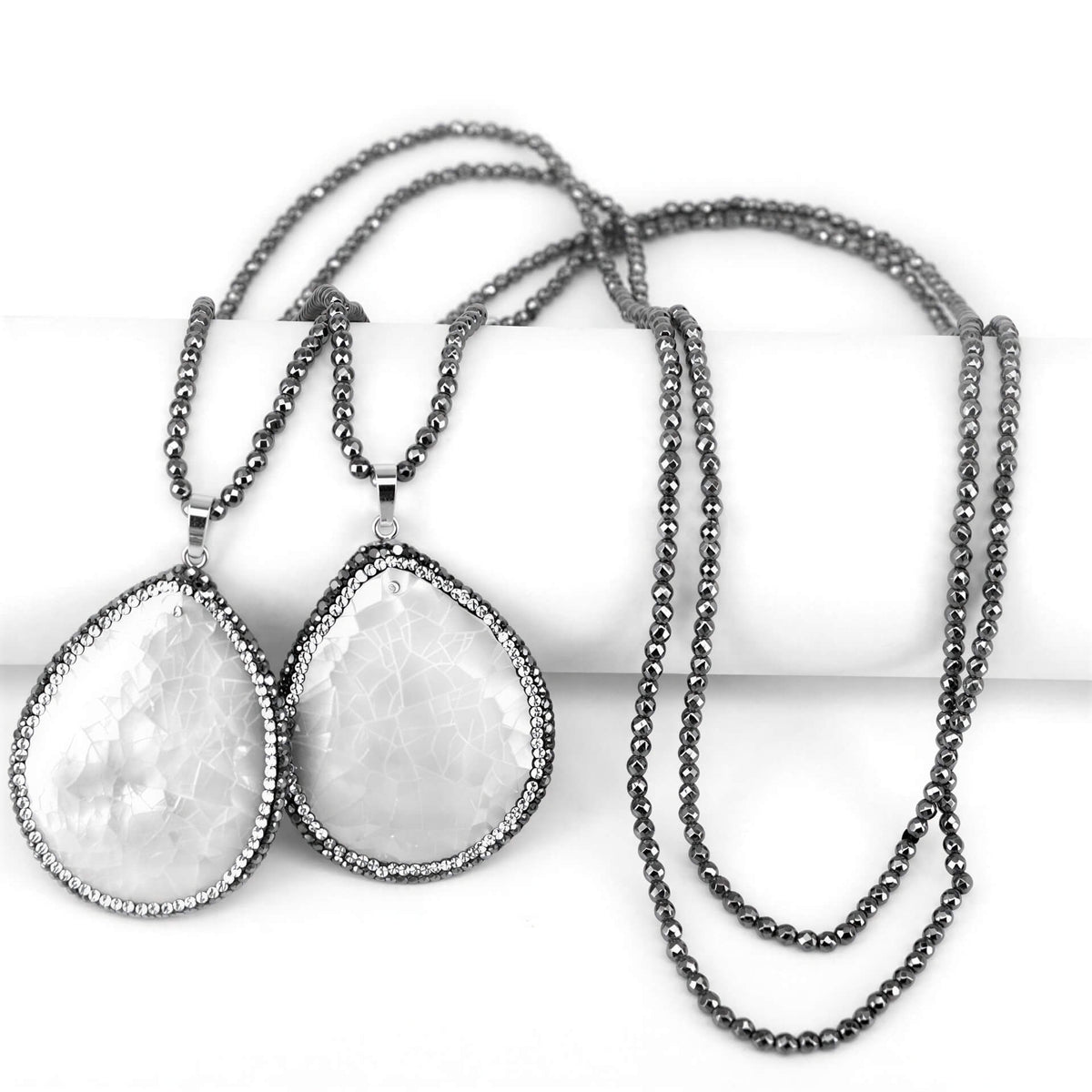 Lange wit parelmoeren ketting met hematiet en stras steentjes liggend op display | Bright White Shell Crackle