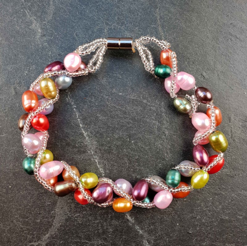 Zoetwater parel armband met vrolijk gekleurde parels en magneetslot liggend op leisteen | set Bonica
