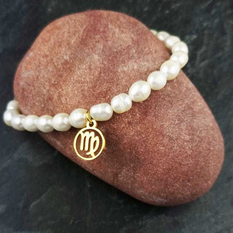 Wit zoetwater parel armband met goud edelstalen bedeltje van sterrenbeeld Maagd liggend op rode steen | Gouden Sterrenbeeld Maagd