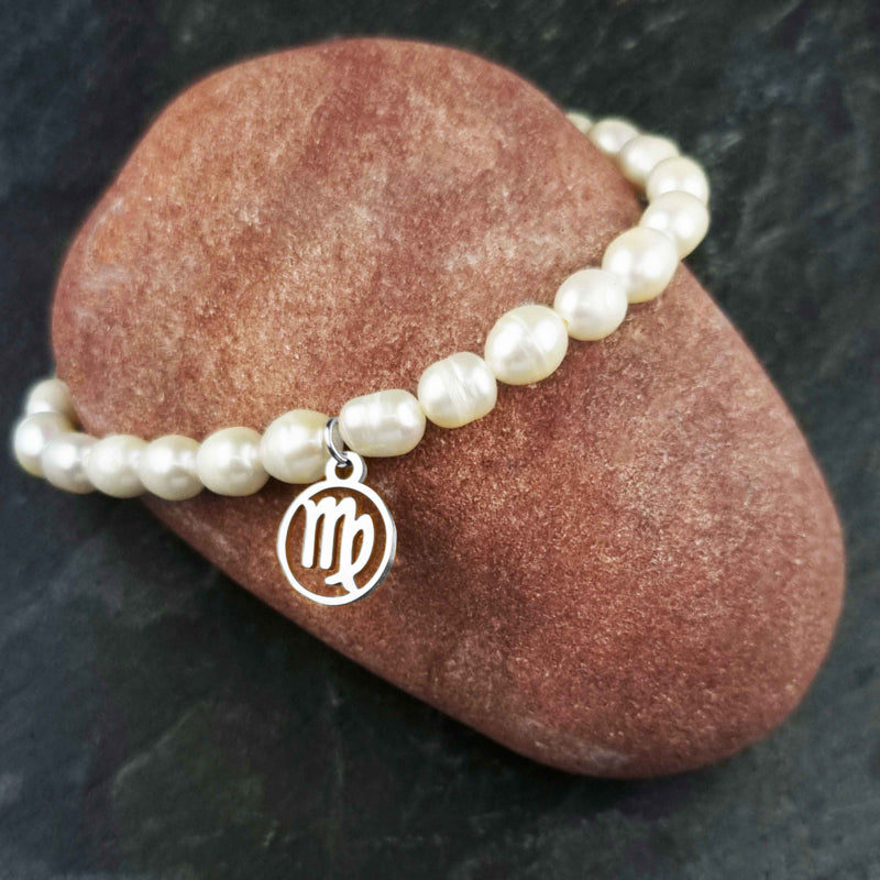 Wit zoetwater parel armband met zilveren symbool van sterrenbeeld Maagd liggend op rode steen | Zilveren Sterrenbeeld Maagd