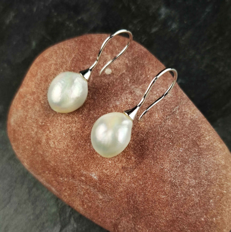 Zoetwater parel oorbellen met witte barok parels en sterling zilver (925) liggend op rode steen | Mayla White