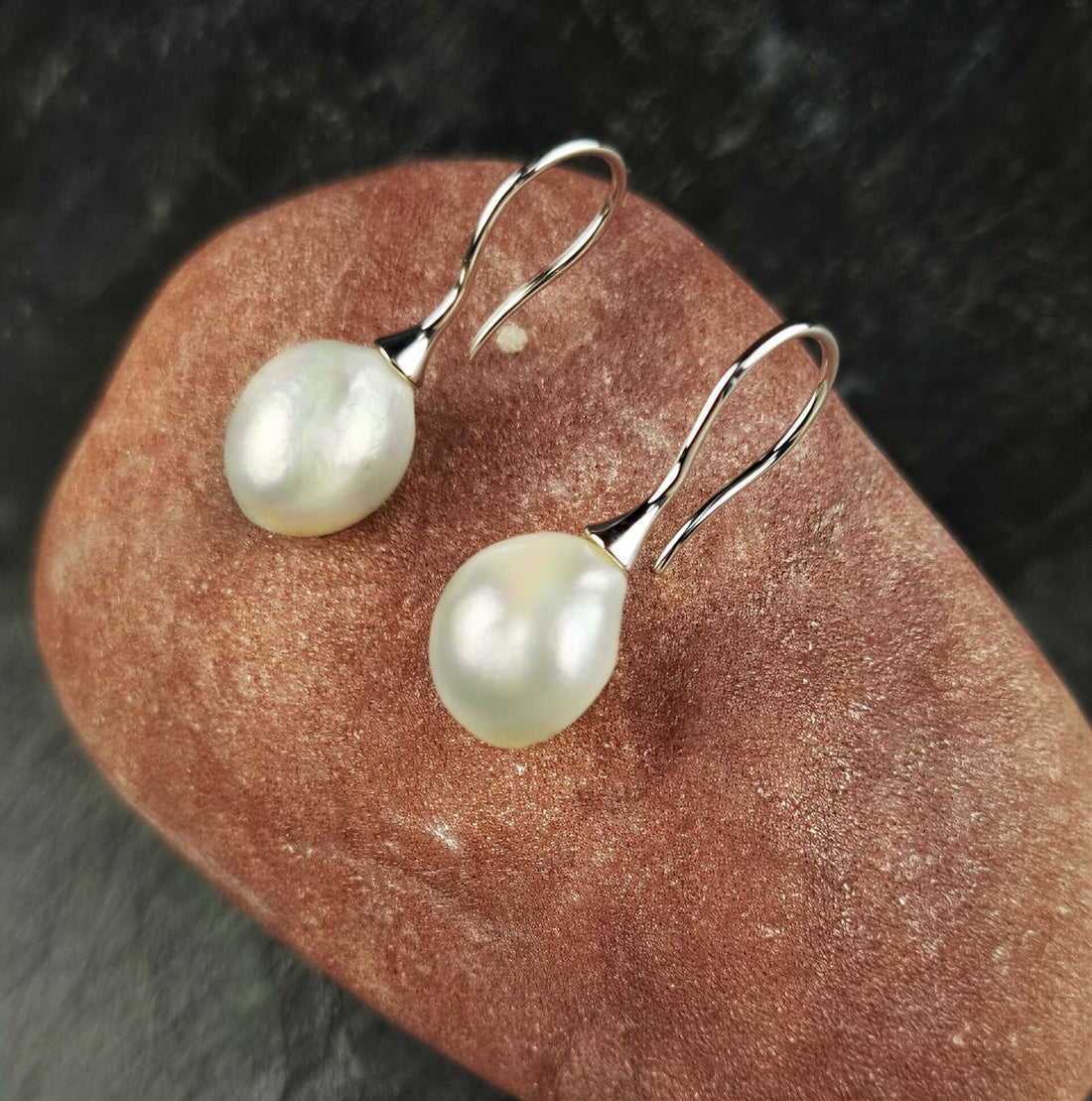 Zoetwater parel oorbellen met witte barok parels en sterling zilver (925) liggend op rode steen | Mayla White