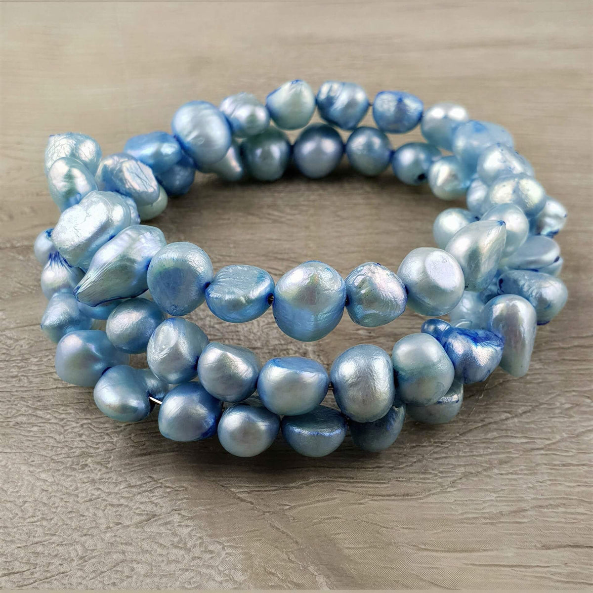 Zoetwater parel wikkel armband met aqua blauwe parels liggend op hout | Zen Aqua