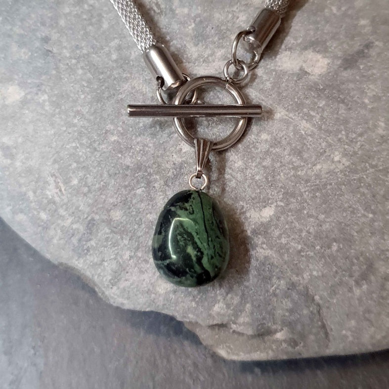Detail van groen zwarte edelstenen ketting met nebula steen aan hanger en zilver edelstaal liggend op kei | Toggle Chain Nebula
