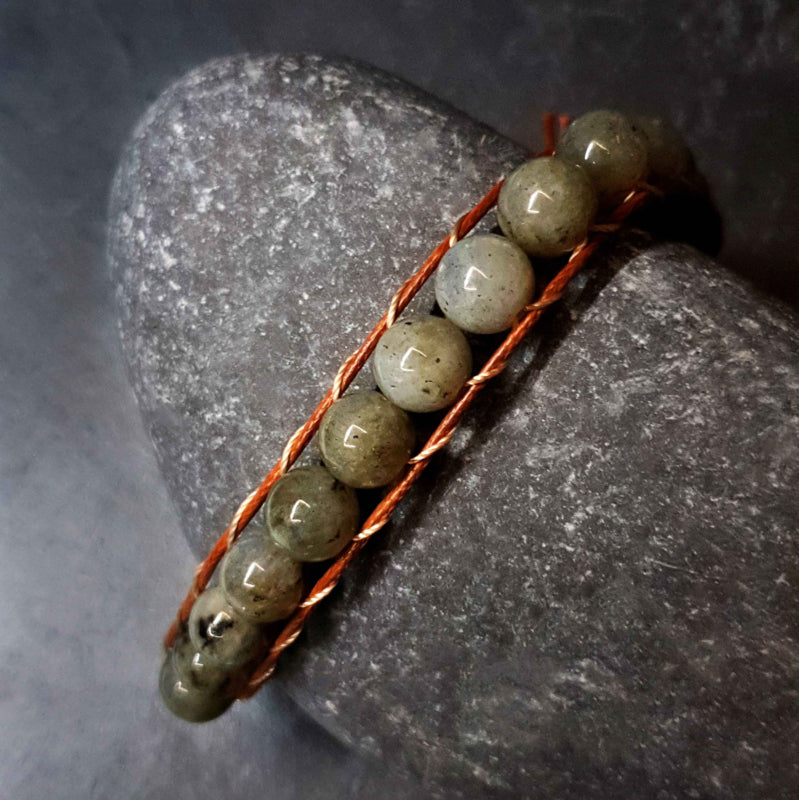 Edelstenen armband met labradoriet en gouden slotje met aum motief liggend op kei | Labradorite Antique Gold
