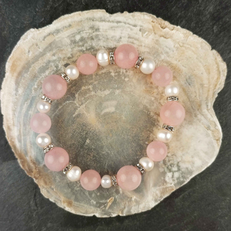 Wit zoetwater parel armband met roze edelstenen rozenkwart en stras steentjes , elastisch, liggend op witte schelp | Bling Paerl W Rose Quartz