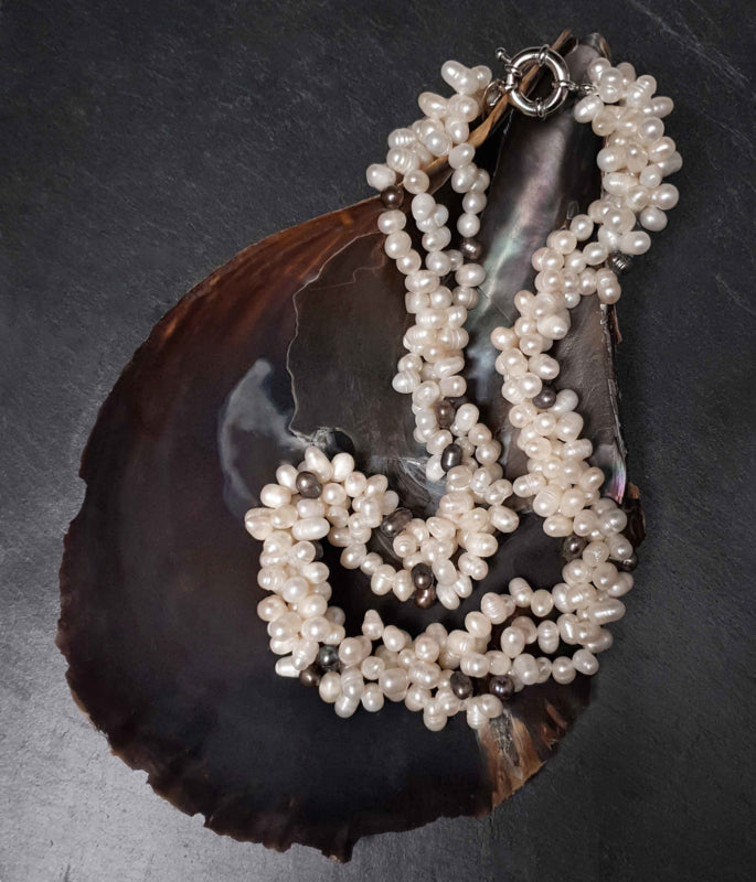 Zoetwater parelketting met witte en zwart blauwe parels in 3 strengen liggend in schelp | Amira