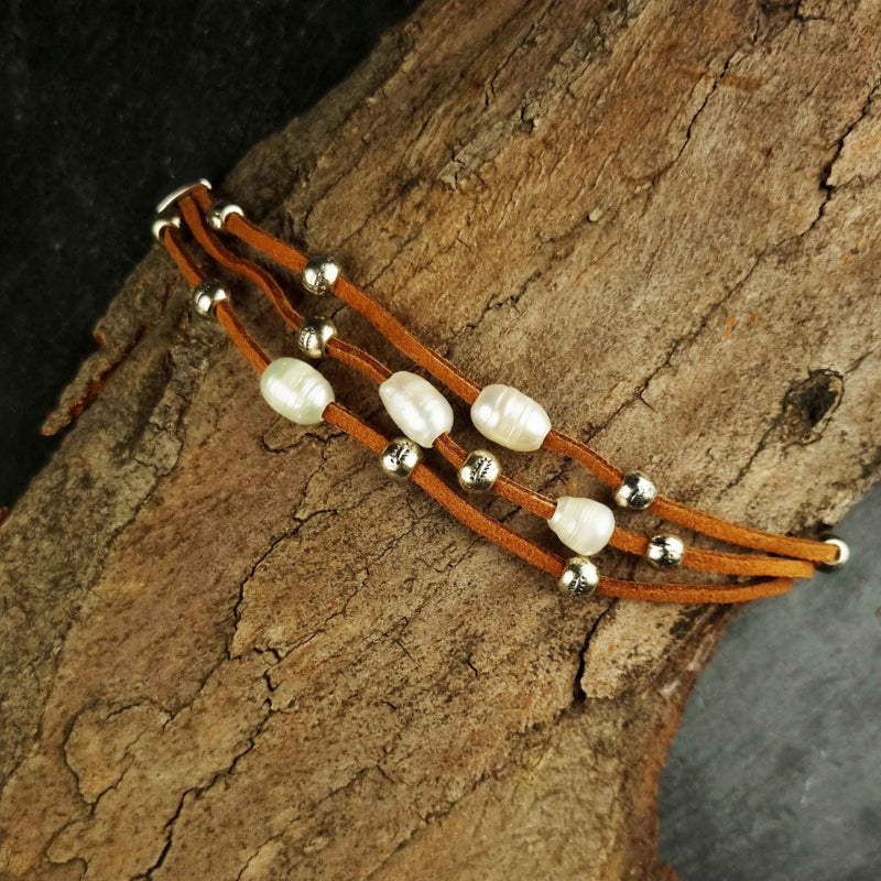 Wit zoetwater parel armband met bruin leer en magneetslot liggend op schors | Aafke
