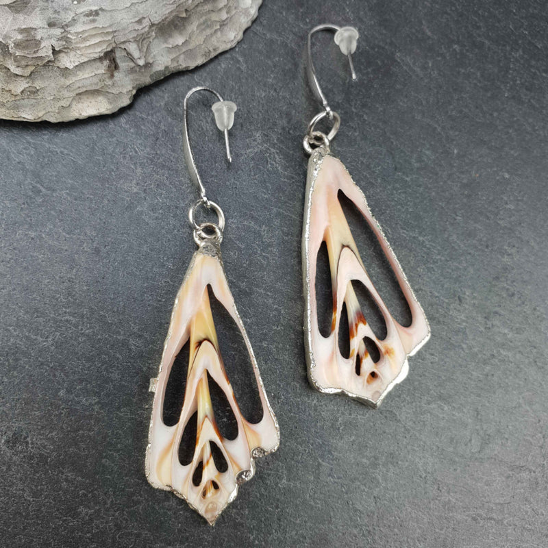 Schelpen oorbellen met zalm roze schelp en zilver edelstaal liggend op steen | Lahuanus Shell Silver