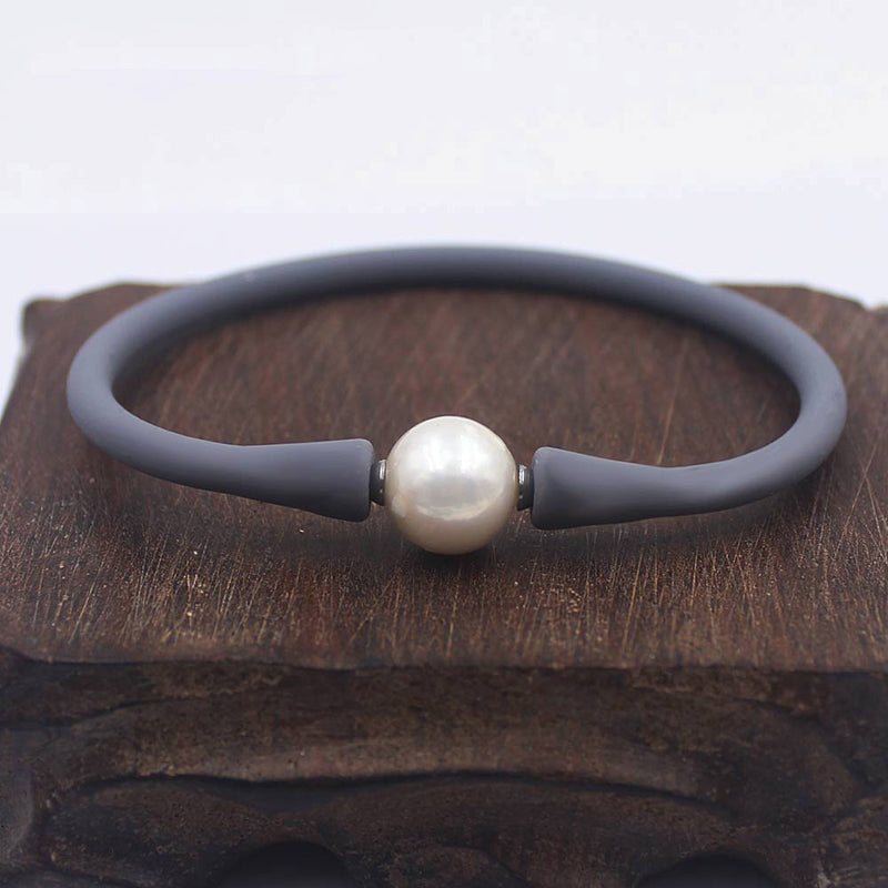 Wit elastisch zoetwaterparel armband met grijze band liggend op hout | Greyly