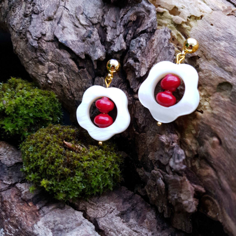 Rood koralen oorbellen met wit parelmoer in bloem vorm en goud edelstaal liggend op hout | Coral Flower