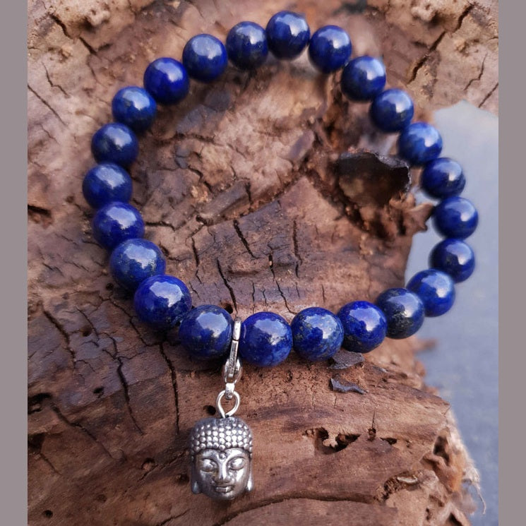 Blauw edelstenen armband met lapis lazuli en boeddha bedeltje liggend op hout | Lapis Lazuli Silver Dangling Buddha Head