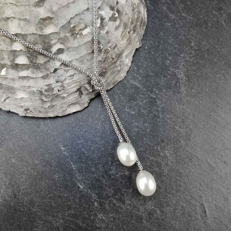 Detail van zoetwater parelketting met witte parels aan sterling zilveren ketting (925) liggend op schelp | Milou