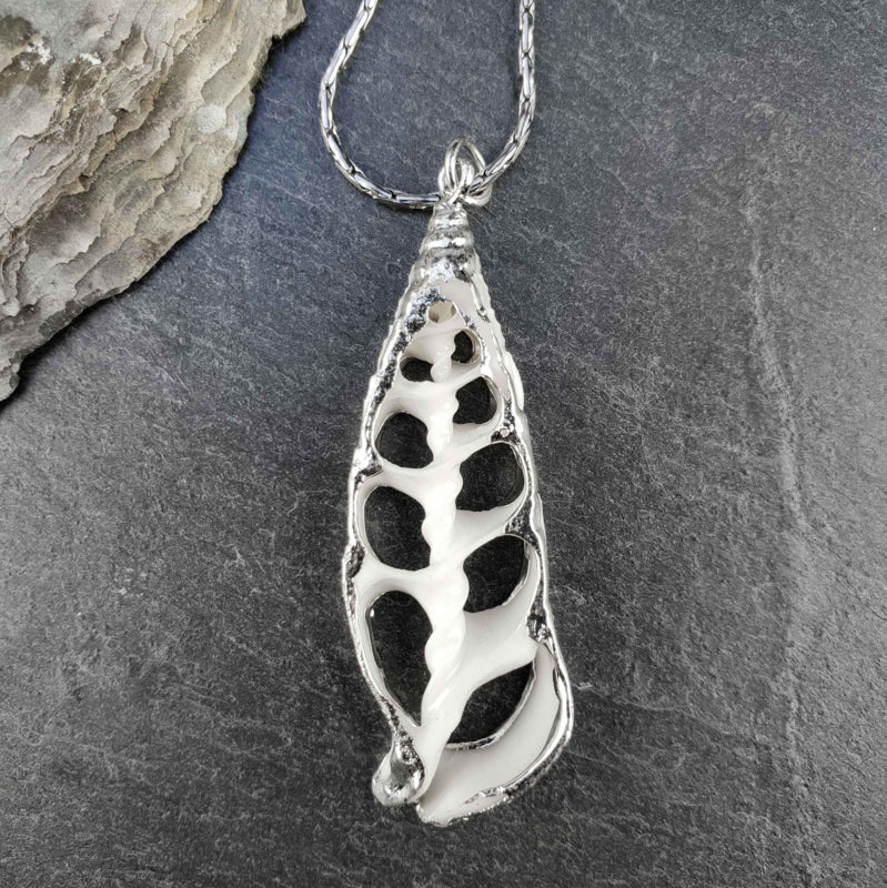 Schelpen ketting met witte schelp hanger en zilver edelstaal liggend op steen | White Trumpet Shell Silver