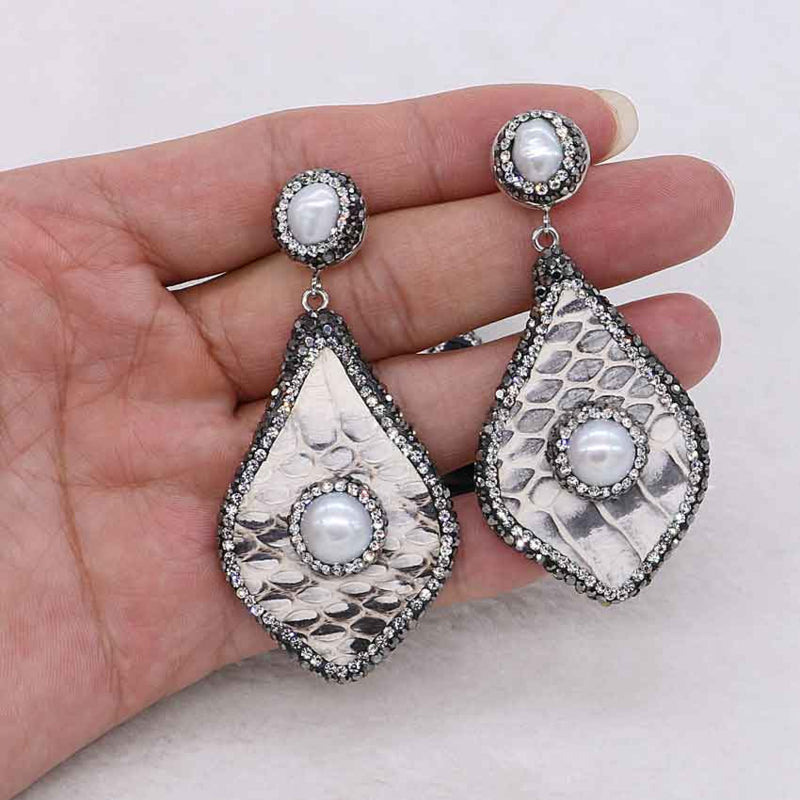 Grote zoetwater parel oorbellen met witte parel en stras steentjes in hand | Bright Pearl Big Snake Leather