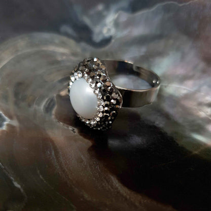 Witte zoetwater parel ring met zwarte stras steentjes liggend in schelp, aanpasbare parel ring, zijaanzicht parel ring