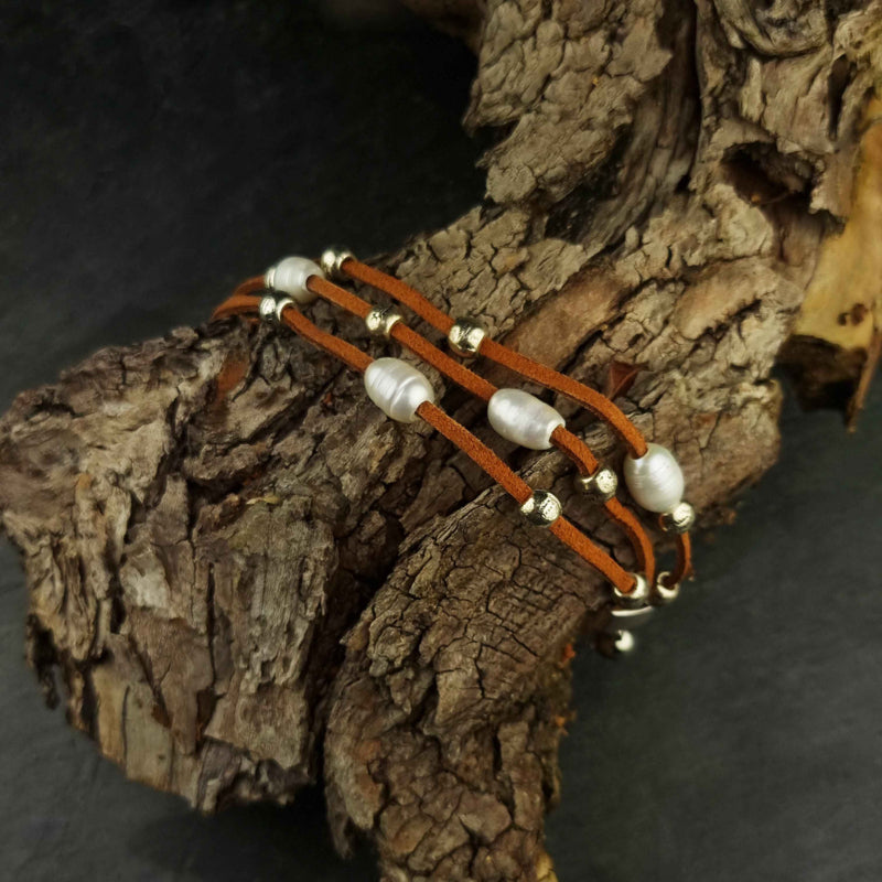 Wit zoetwater parel armband met bruin leer en magneetslot liggend op stronk | Aafke