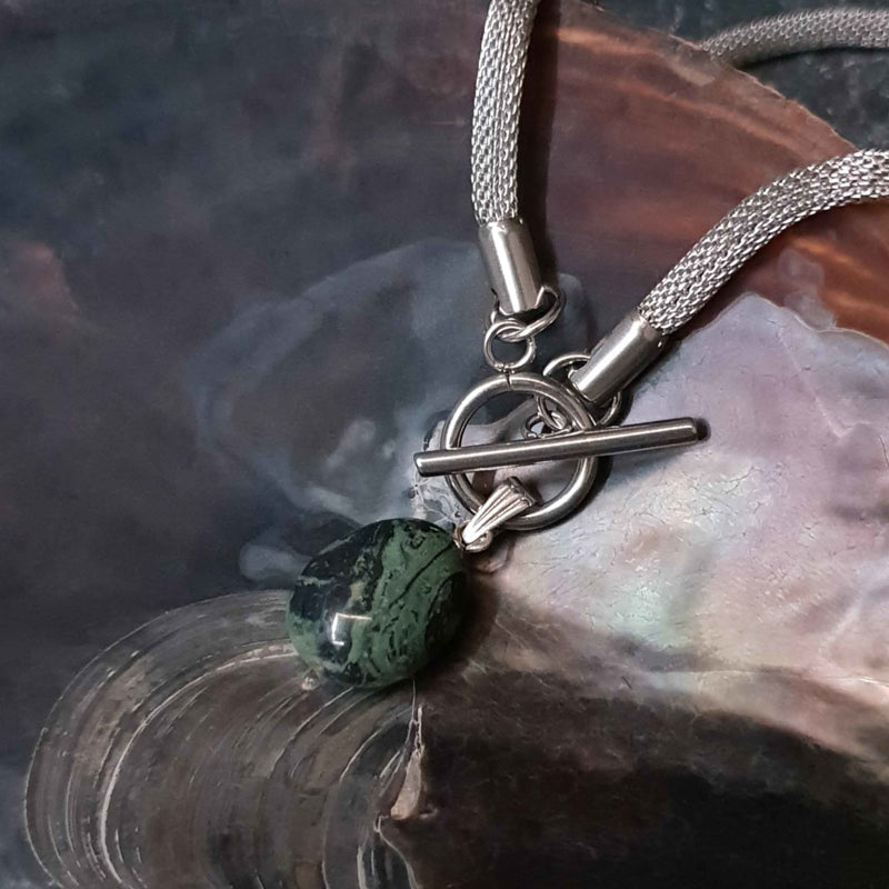Detail van groen zwarte edelstenen ketting met nebula steen aan hanger en zilver edelstaal liggend in schelp | Toggle Chain Nebula