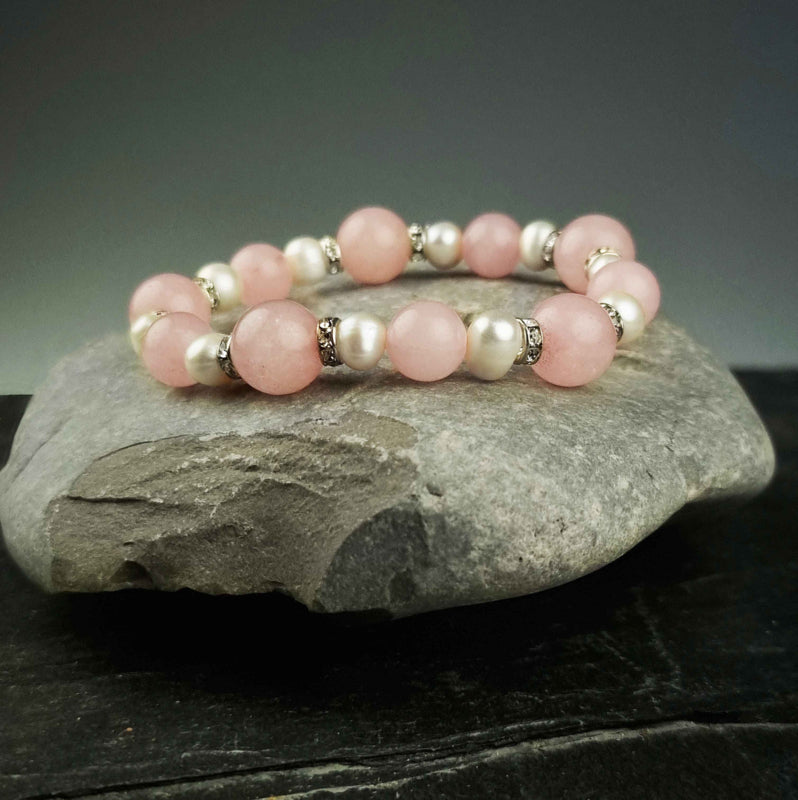 Wit zoetwater parel armband met roze edelstenen rozenkwart en stras steentjes , elastisch, liggend op kei | Bling Paerl W Rose Quartz