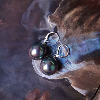 Petroleum kleurige ronden parel oorbellen met zilver edelstaal liggend in schelp, parel oorhanger, zijaanzicht